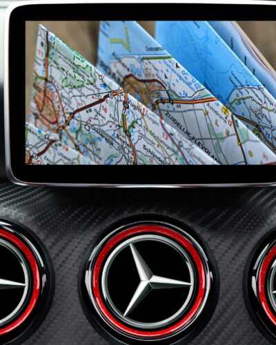 GPS tracking dashboard with smartphone displaying map mounted above three Mercedes-Benz steering wheels with red and silver emblems on carbon fiber background