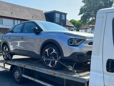 Silver car being recovered on a flatbed truck