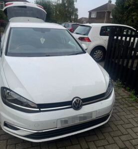 Front view of a white Volkswagen parked on a residential driveway