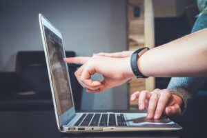 person pointing in a laptop