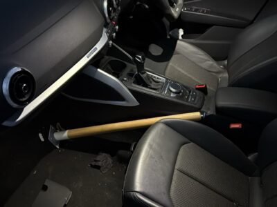 Baseball bat weapon found inside recovered car on black leather driver seat near steering wheel and center console