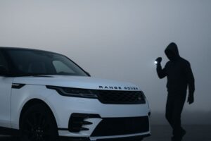 Range Rover with suspicious hooded person holding flashlight at night